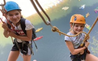 Descente rappel en duo au dessus de la rivière tapissée de canoës multicolores